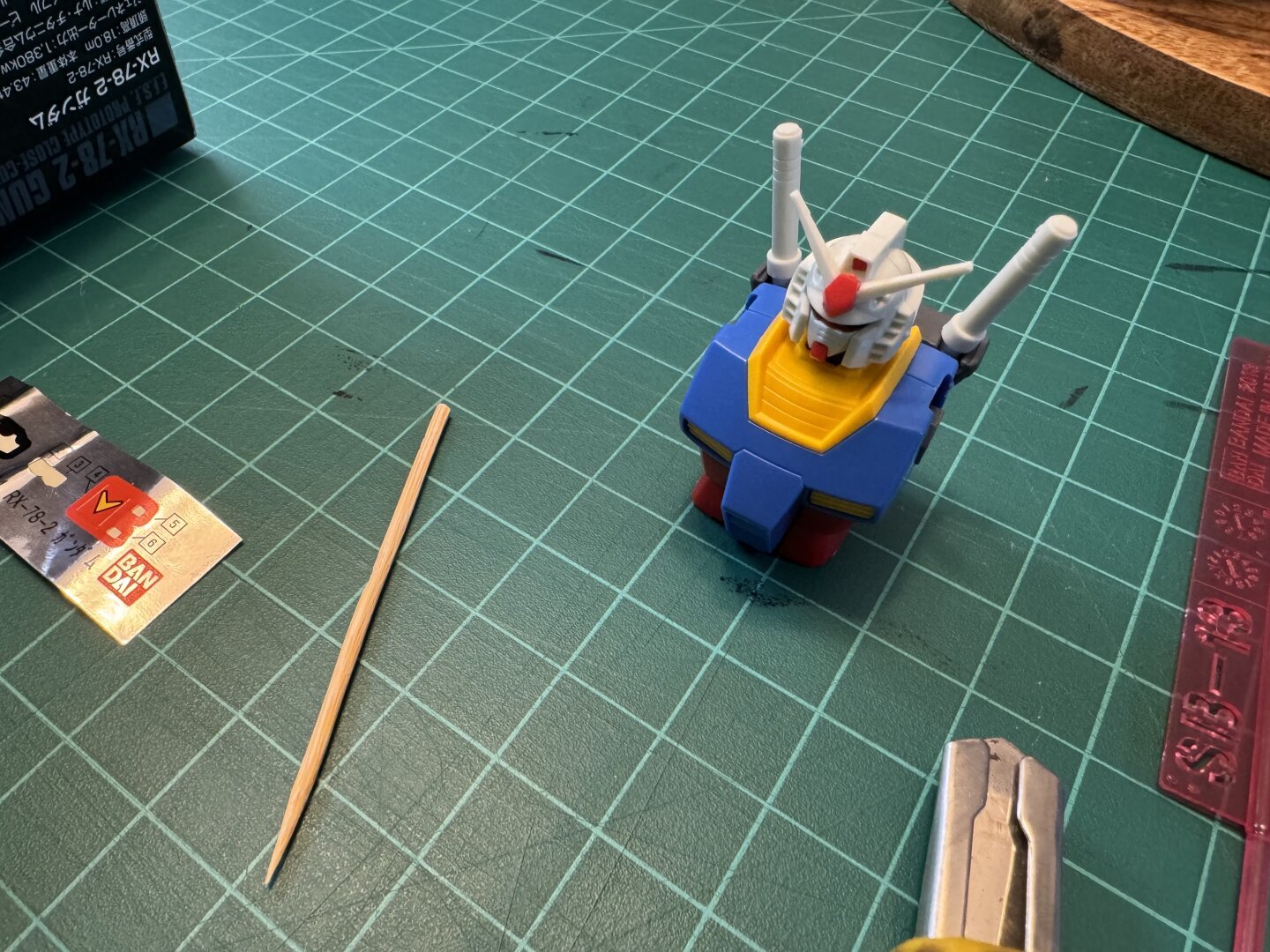 A semi-built Gundam model sitting on a cutting mat.