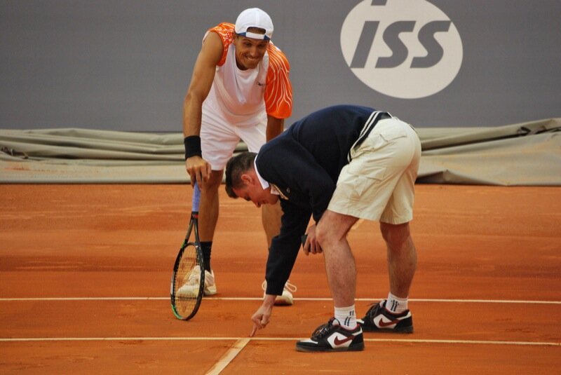 The referee of a match at the Madrid Masters 1000 (2009) points out where the ball bounced, while one of the players watches attentively.