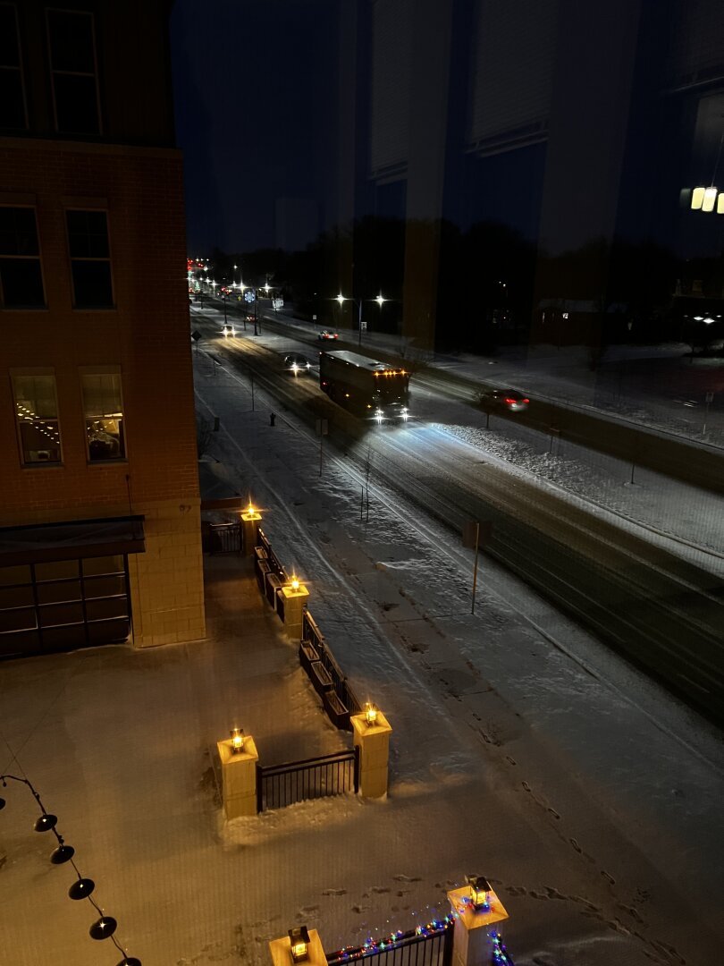 A photo out of my apartment window showing a bus on the snowy road at night