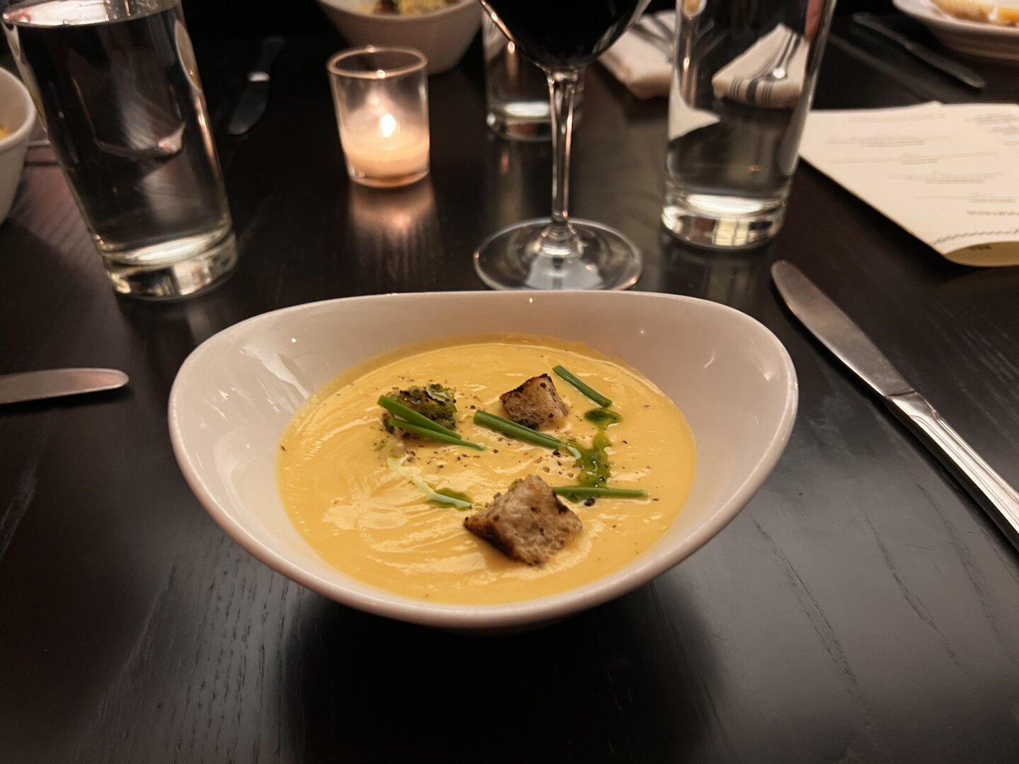 A rutabaga beer cheese soup with croutons in a white bowl