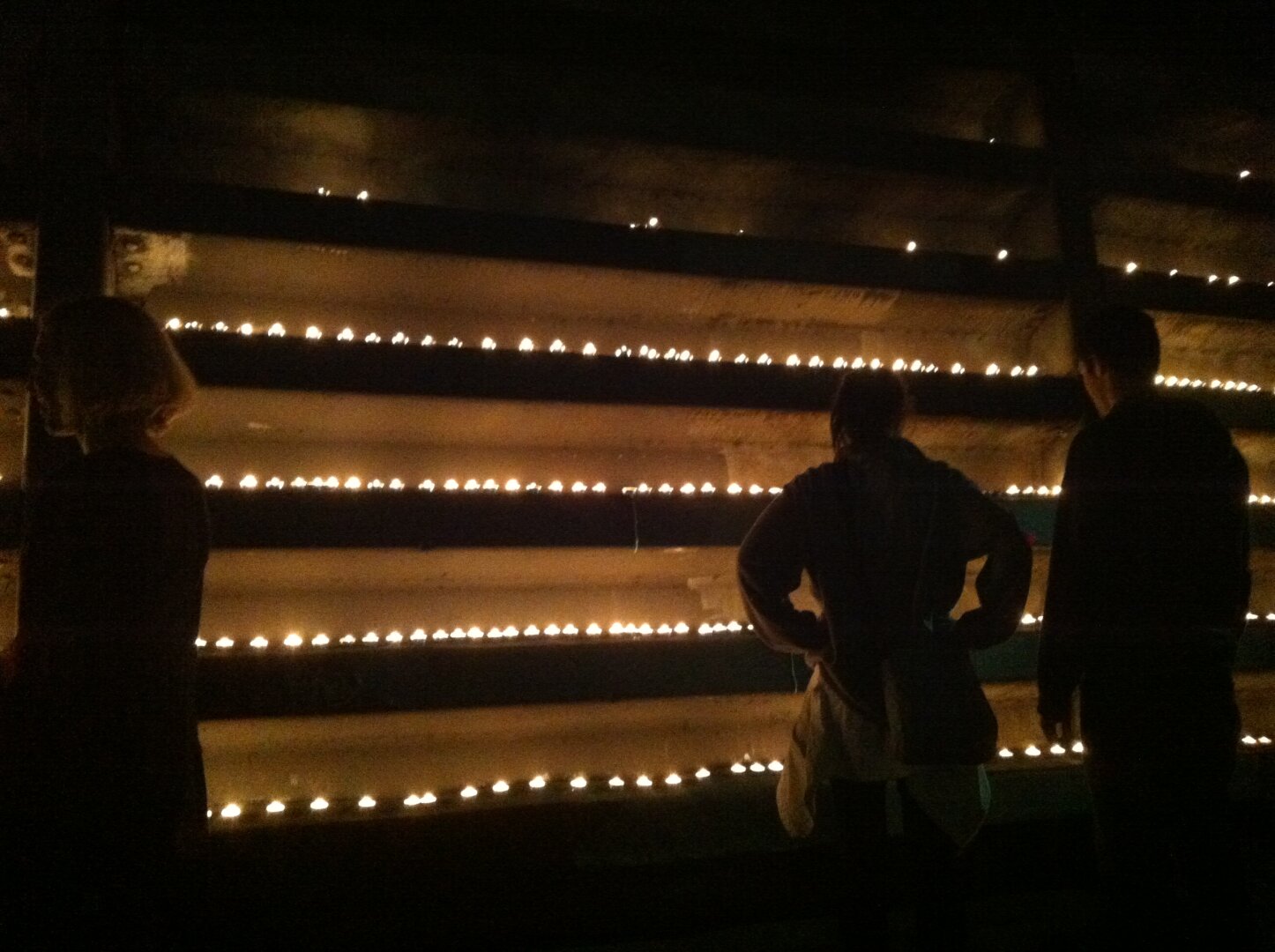 People add to rows of lit candles