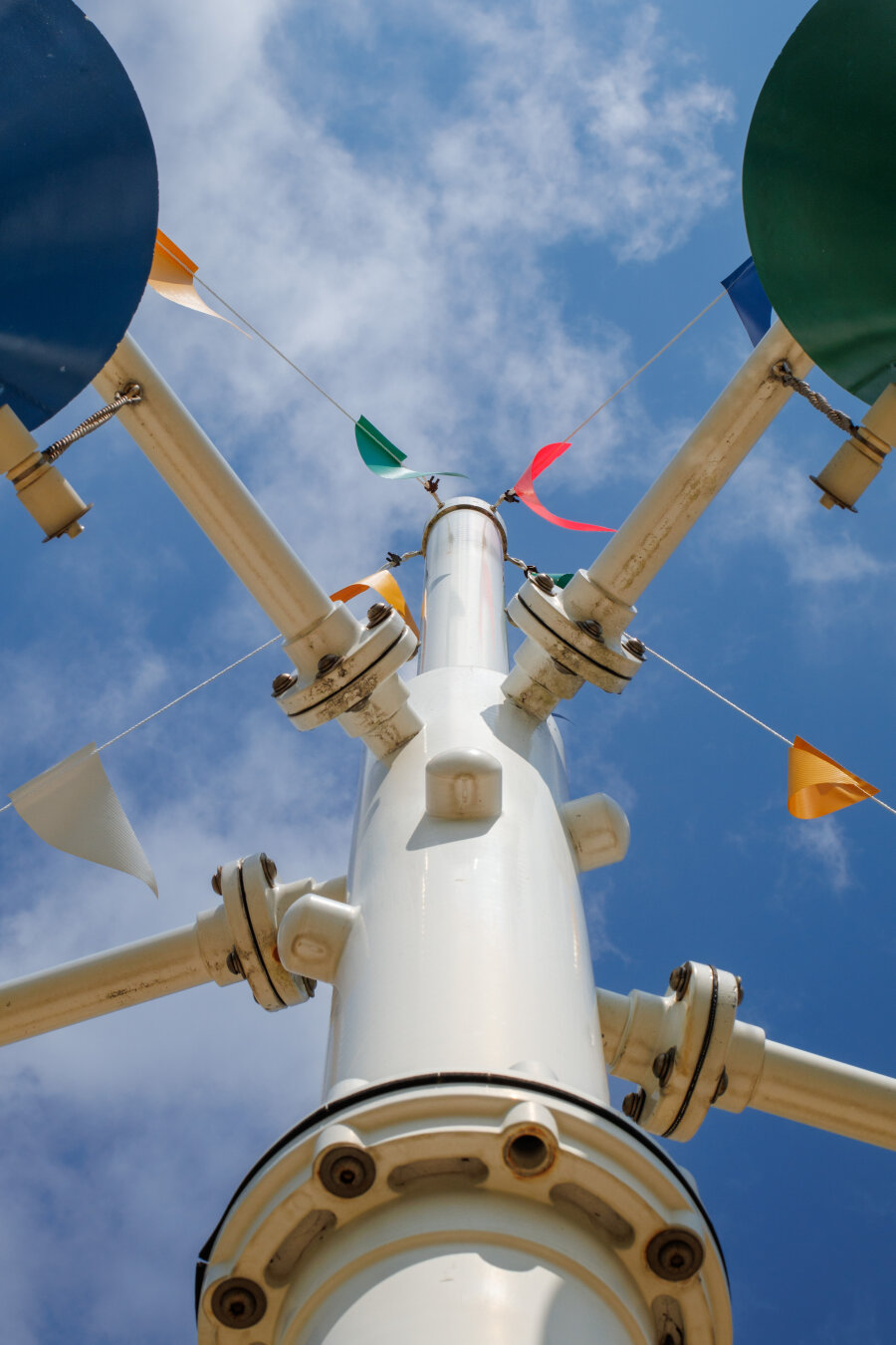 Looking up at the main post of a splashpad tower thing. Blue sky with some wispy clouds above.