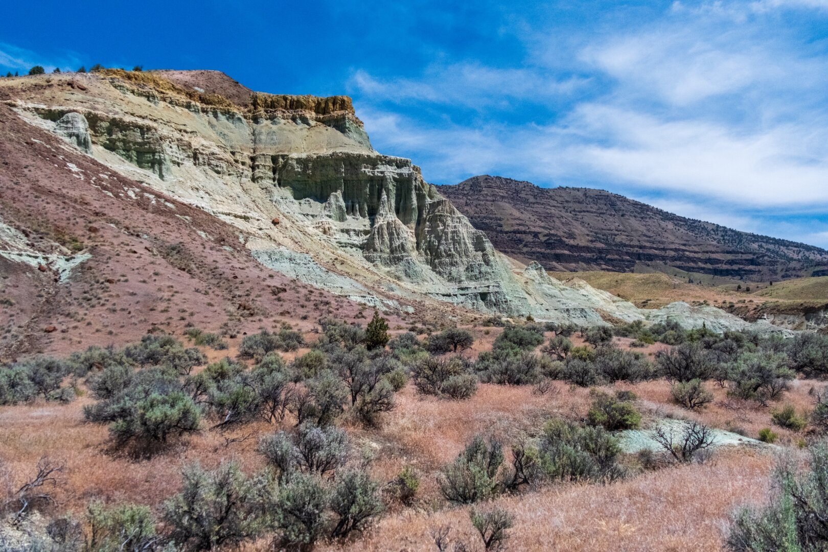 Interesting green rock sits above dry sage. [Fuji X-T5 / Tamron 18-300]