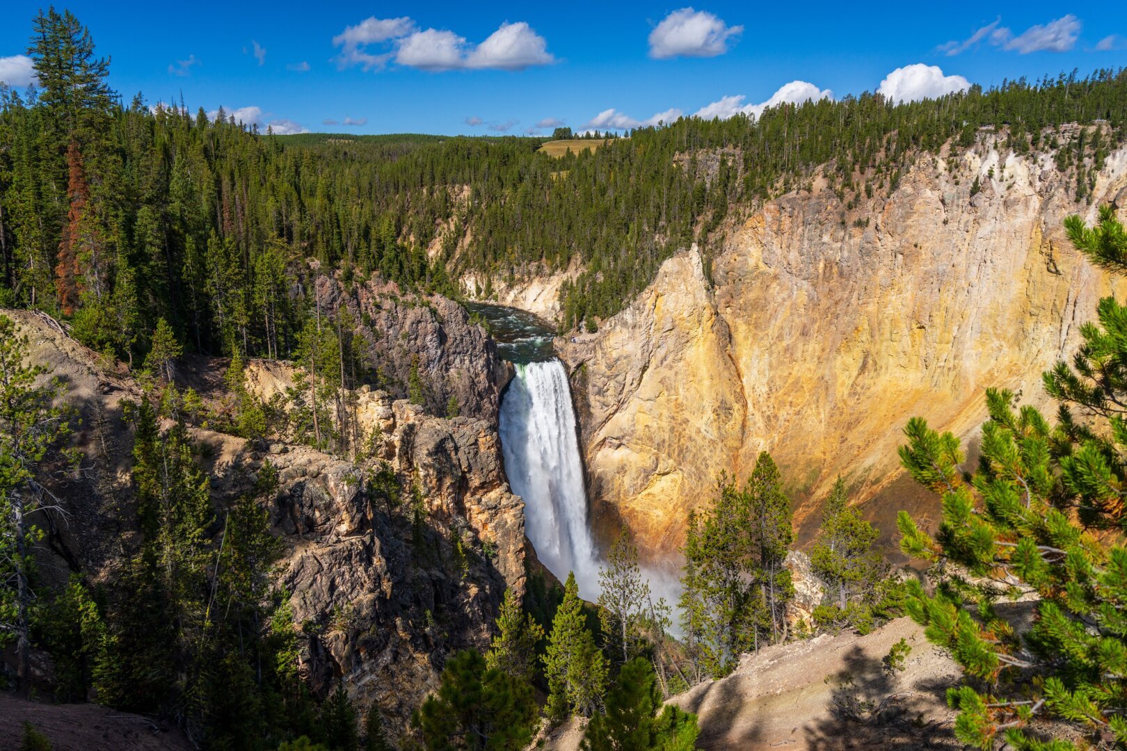 A large waterfall in the middle of trees and a yellowey, stoney canyon. [Sony A7R V / Tamron 25-200]