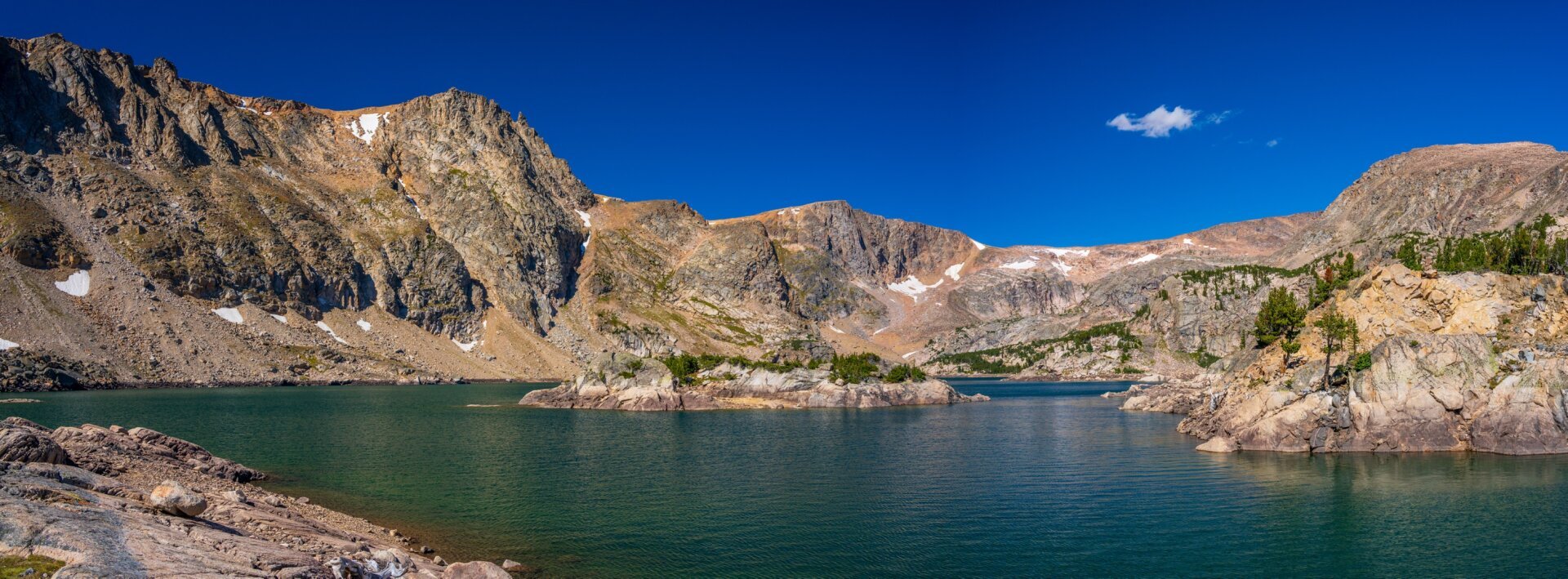 A lake ringed with rocky mountainsides, with an island in the middle. [Sony A7R V / Tamron 25-200]