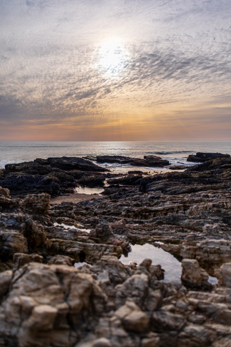 The sun sets over chunky rocks, with the sea behind. [Fuji X-T5 / Sigma 17-40 1.8]