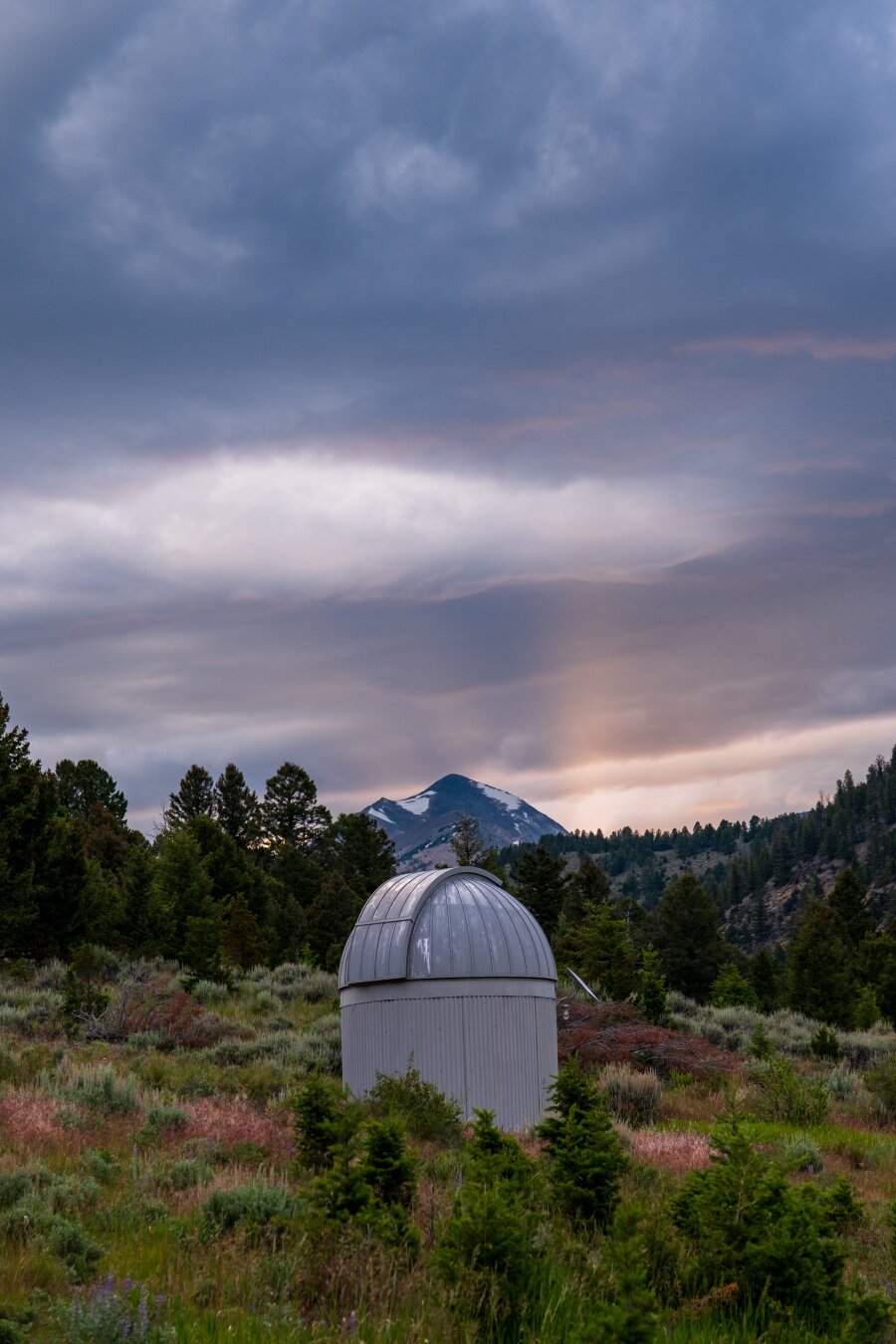 A telescope dome sits in front of a mountain, with dramatic clouds. [Fuji X-T5 / Sigma 17-40 1.8]