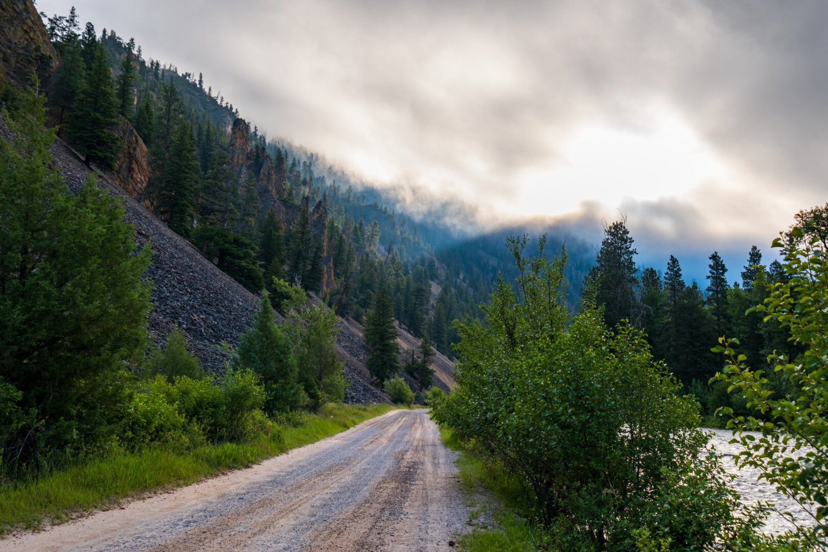 Clouds gather over a dirt road by a river. [Fuji X-T5 / Fuji 10-24 WR]