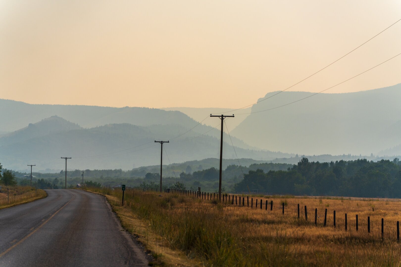 A smoky landscape in the distance, viewed from a highway. [Sony A7R V / Tamron 25-200]