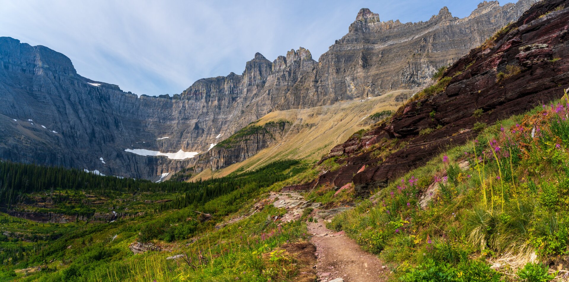 A path runs through greenery toward a large ring of mountains in the distance. [Sony A7R V / Tamron 25-200]
