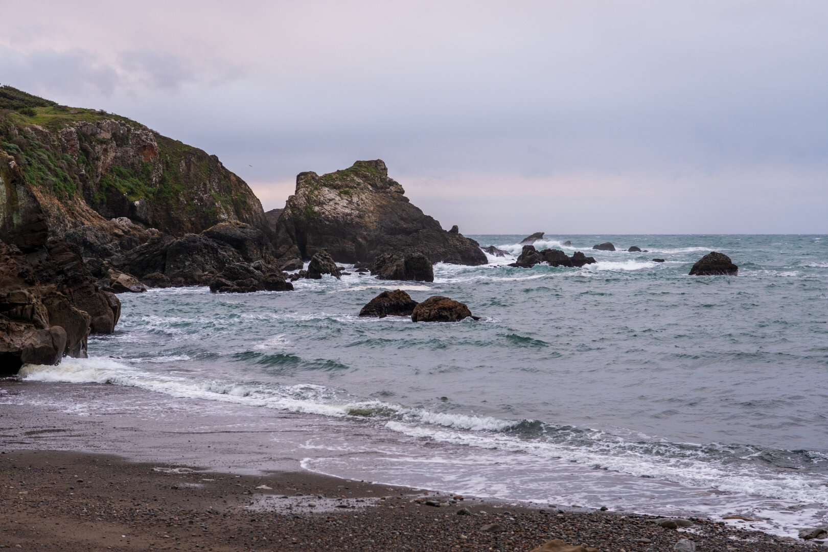 Rocks stretch from a beach into the sea. [Fuji X-T5 / Sigma 17-40 1.8]