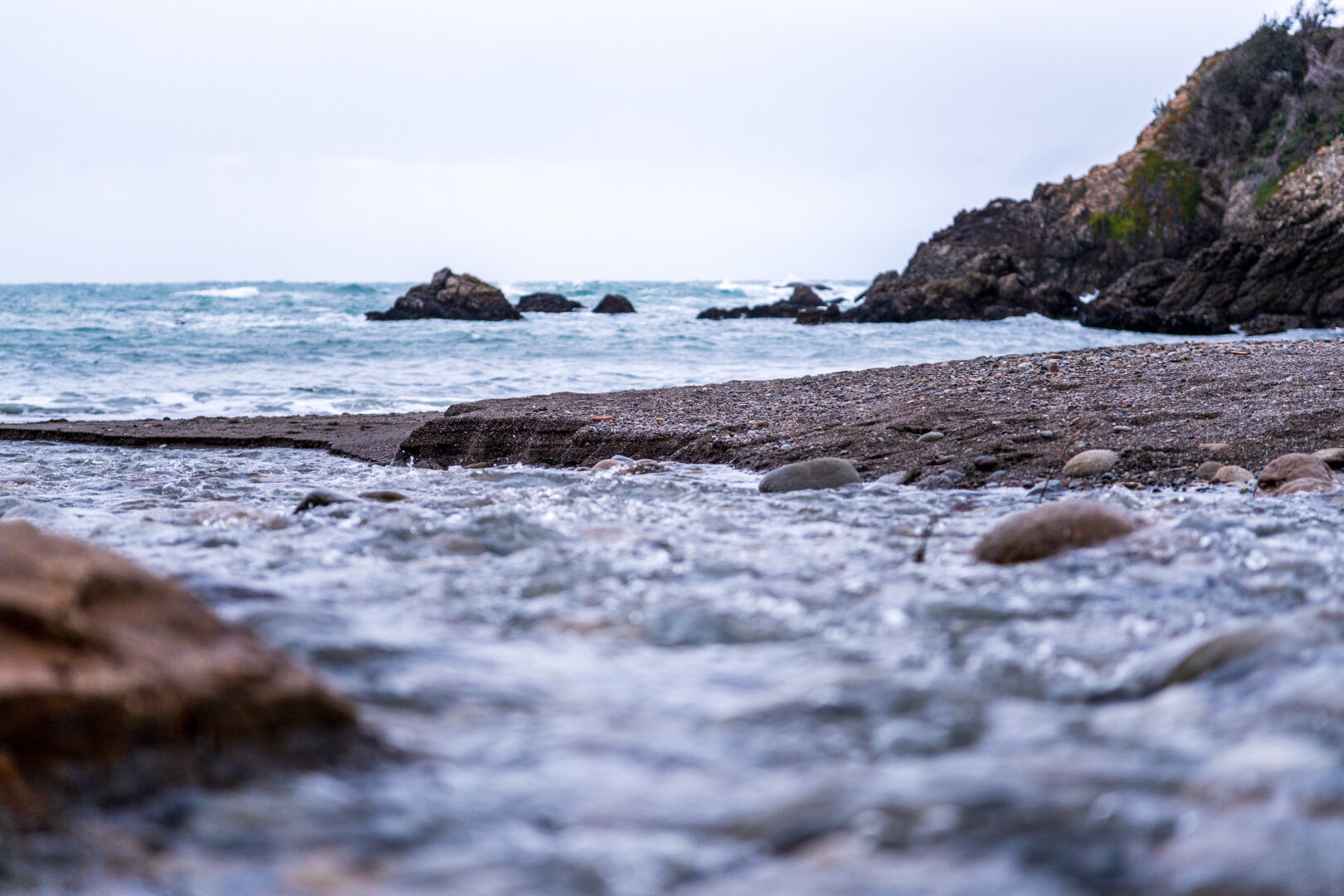 A rocky strip in-focus between blurry waters. [Fuji X-T5 / Sigma 17-40 1.8]