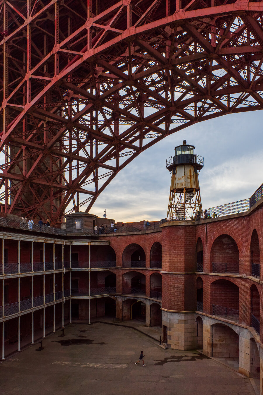 An older brick building with a large latticework orange construction overhead. [Ricoh GR III]