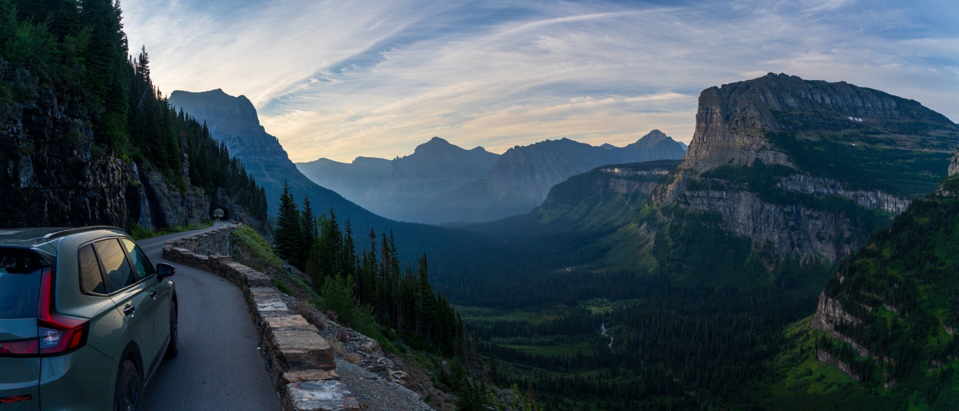 A panoramic view of a wide canyon between steep mountains, with a road and tunnel visible on the left edge. [Sony A7R V / Tamron 25-200]
