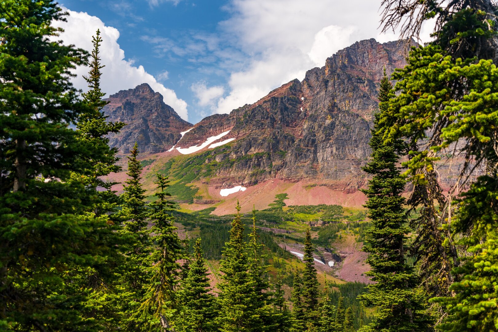 Mountains peer through trees, with cloudy skies behind. [Sony A7R V / Tamron 25-200]