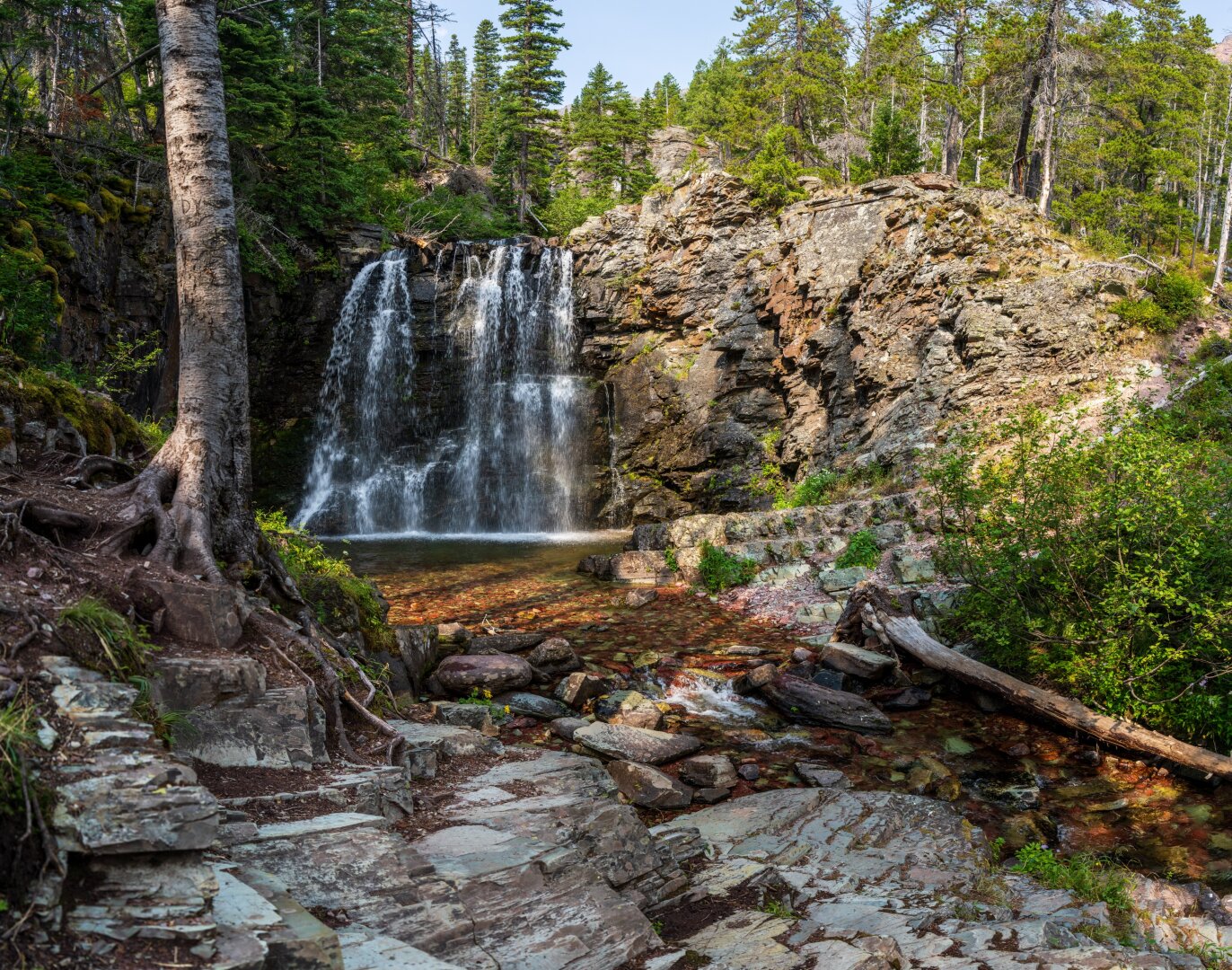 A large waterfall runs down a rocky face, with its pool in the center of frame. [Sony A7R V / Tamron 25-200]