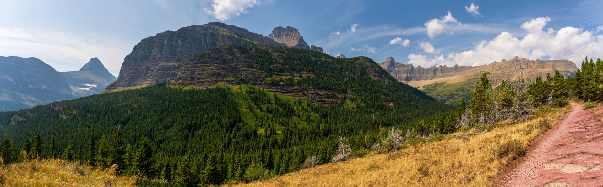 A panoramic picture shows a large rocky outcrop standing above trees, with a trail wrapping beside it. [Sony A7R V / Tamron 25-200]