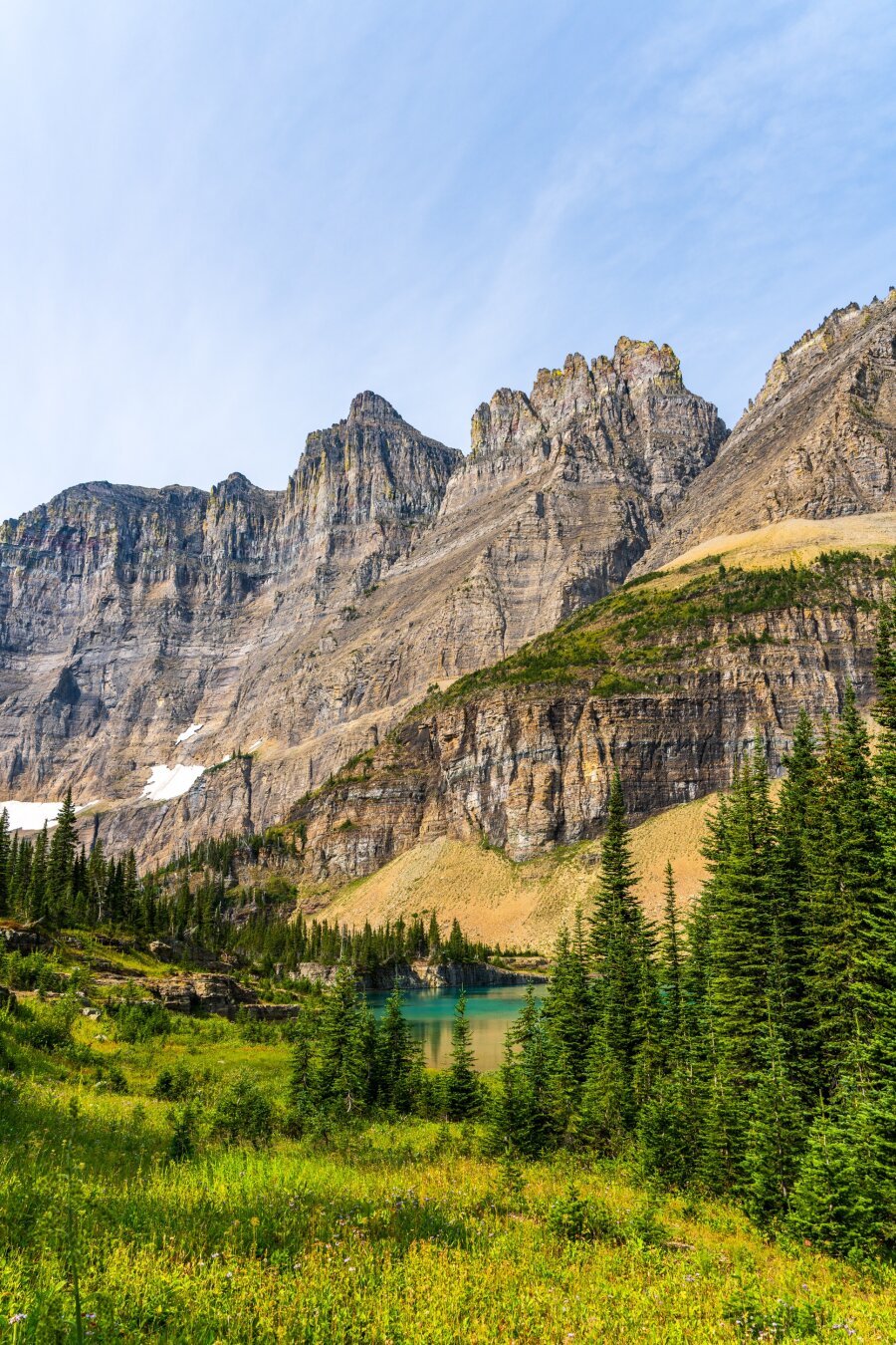 Mountains climb behind a small lake, ringed by trees and grass. [Sony A7R V / Tamron 25-200]