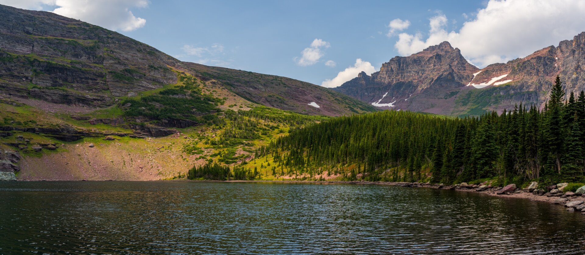 A lake ringed by trees and mountains on one side, and a large ridge on the other. [Sony A7R V / Tamron 25-200]