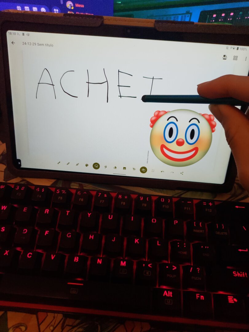 Homem segurando uma caneta touch em frente a um tablet com a palavra achei e um ícone de palhaço