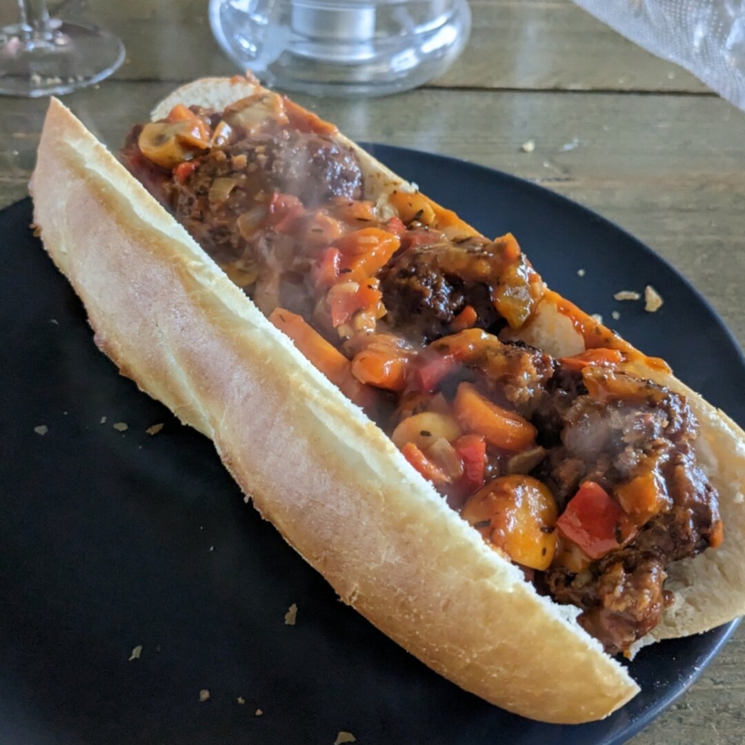 Picture of a steaming baguette with meatballs in tomatonsauce inside