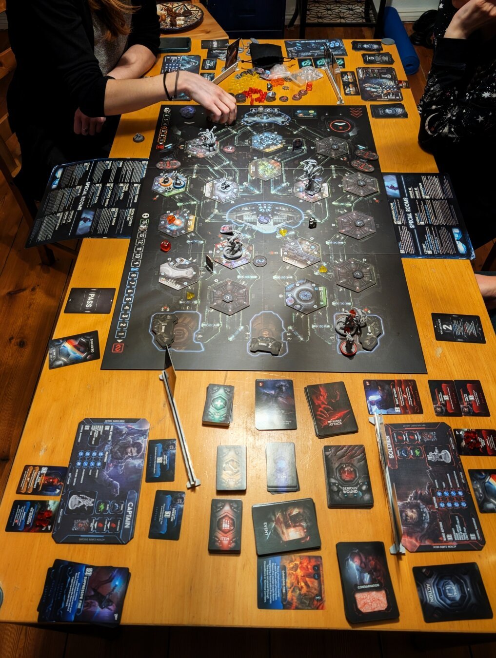 A large table filled with the Nemesis board and various stacks of cards and player mats.