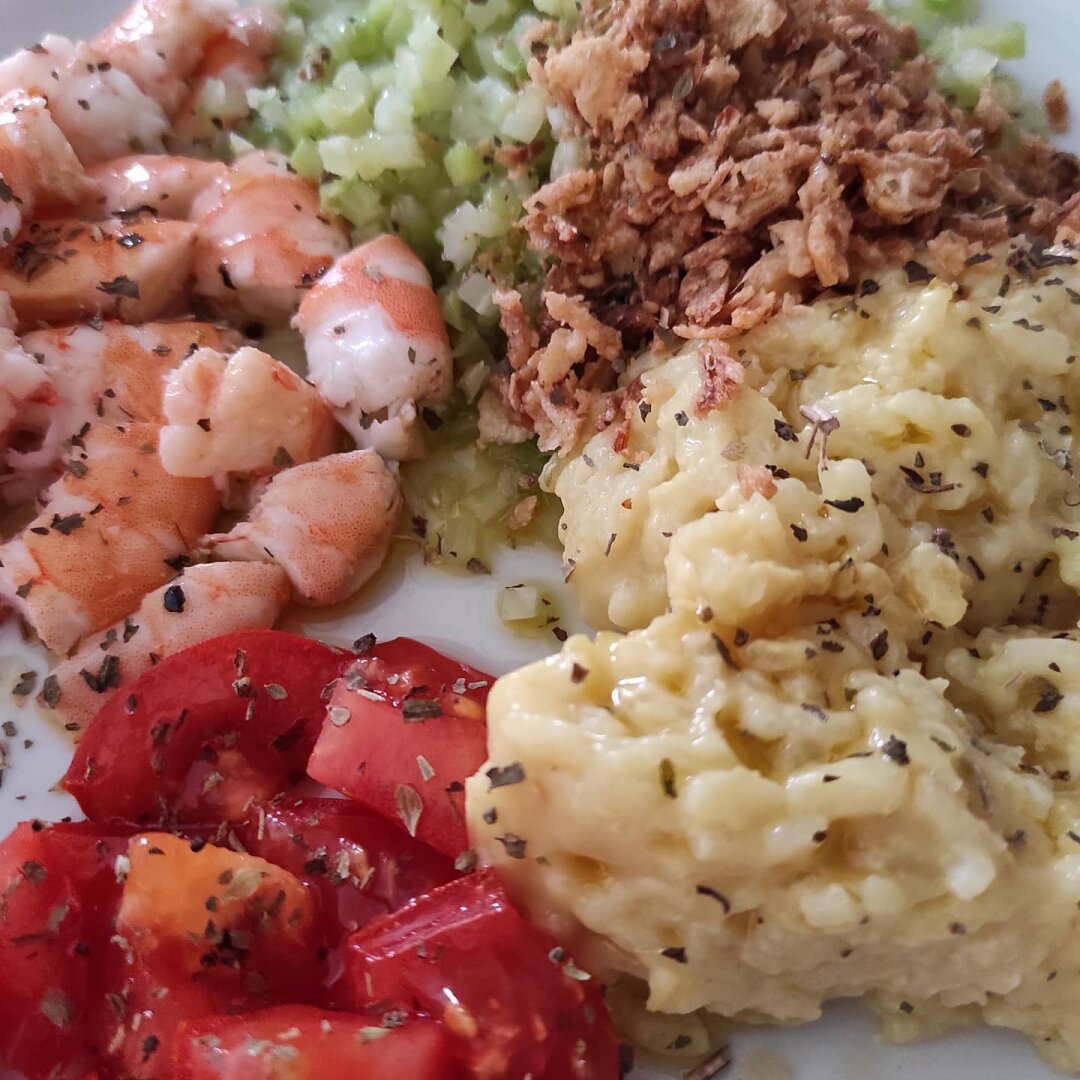 Detalle de la comida abajo tomate, langostinos cocidos y troceados a la izquierda, arriba brócoli en daditos y a su derecha crujiente de cebolla y a la derecha del plato arroz.