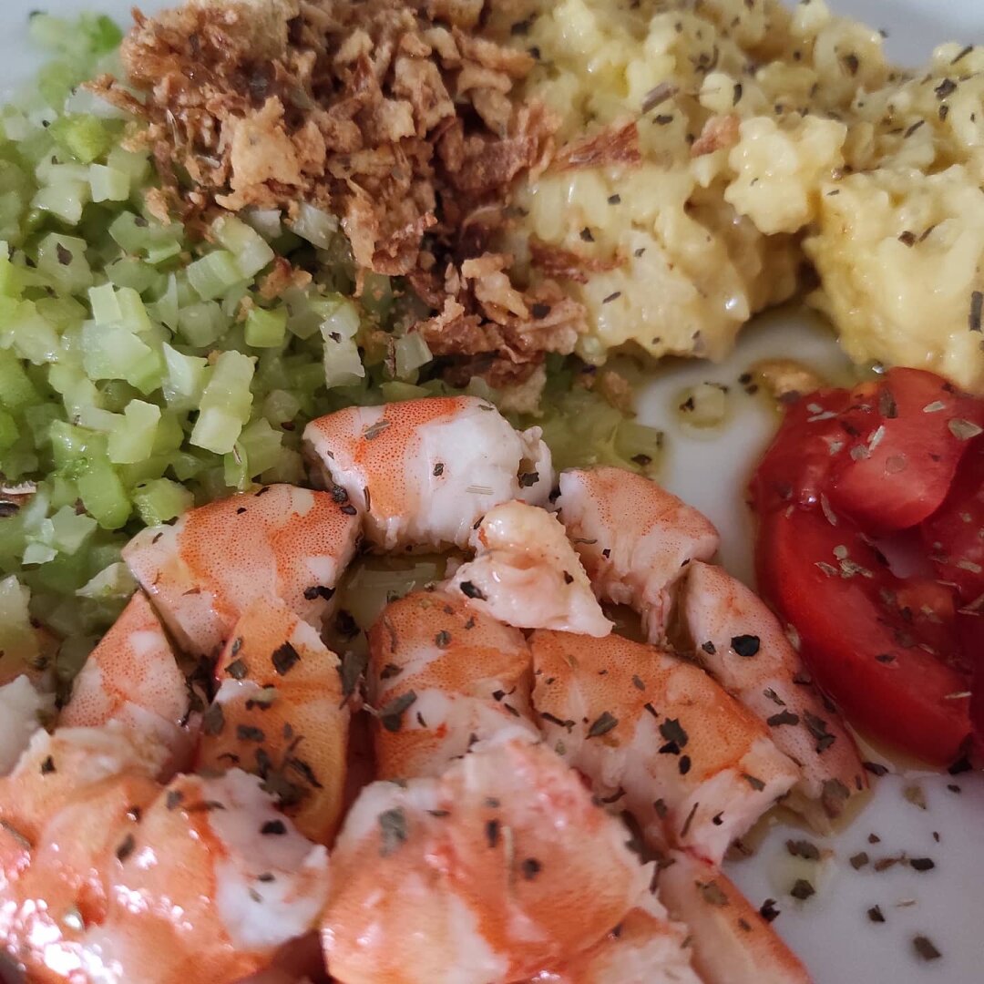 Detalle de la comida a la derecha tomate, langostinos cocidos y troceados abajo, a la derecha brócoli en daditos y arriba crujiente de cebolla y a su derecha arroz.