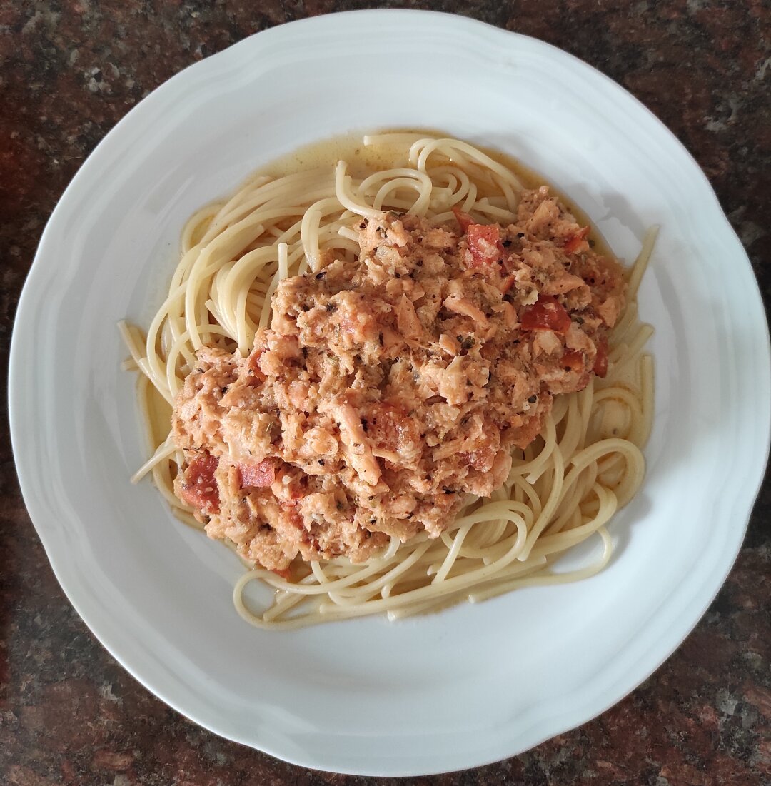 Plato de porcelana blanca con espagueti con con salmón desmigado.