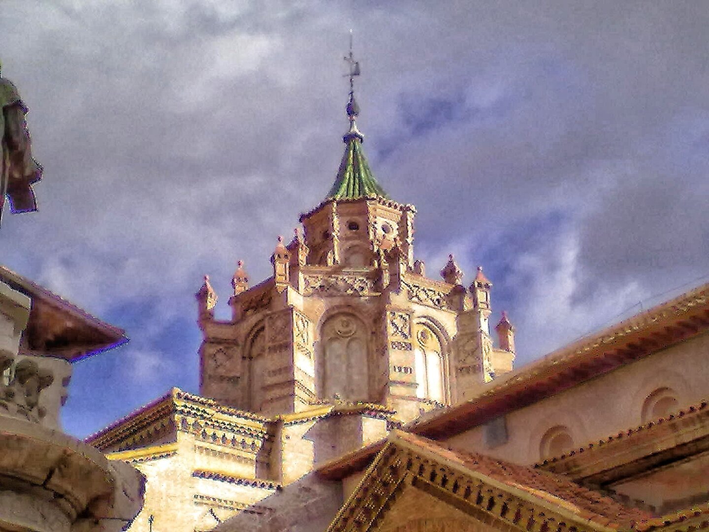 Cimborrio mudejar de la catedral de Teruel con un cielo nublado de fondo y algunos claros entre las nubes.