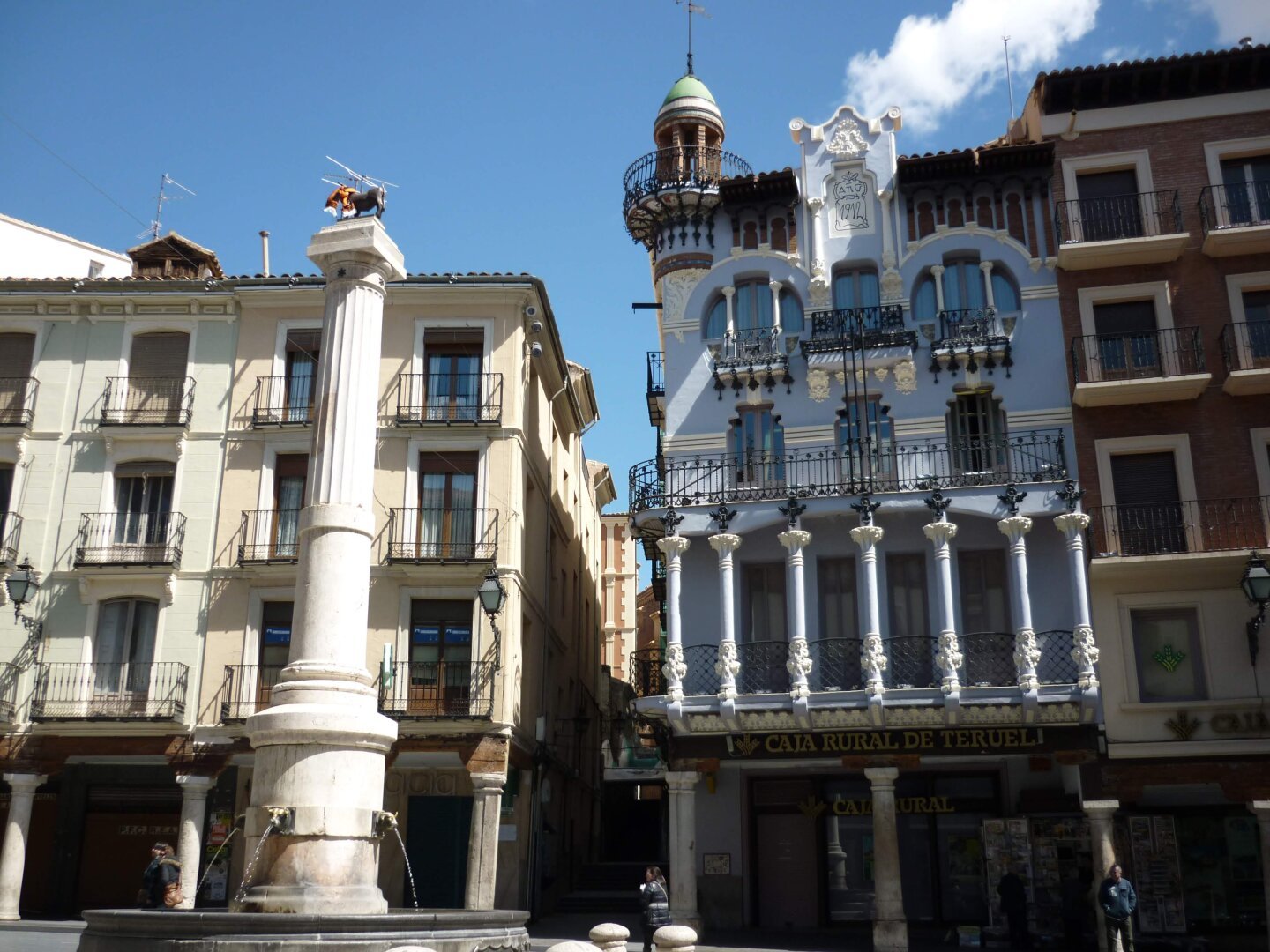 La casa del Torico al fondo a la derecha de la imagen y al frente a la izquierda la columna con el Torico en la parte superior. Día soleado y cielo despejado.