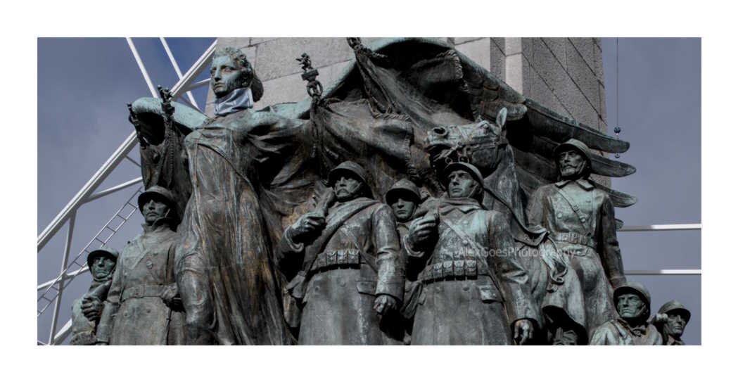 Close up on Monument à la Gloire de l’infanterie belge, a monument in Brussels commemorating the Belgian infantry who fought during first and second world wars. The close up is on the bronze figures of the soldiers in World War I attire stands under the wings of a female figure who represents Victory.