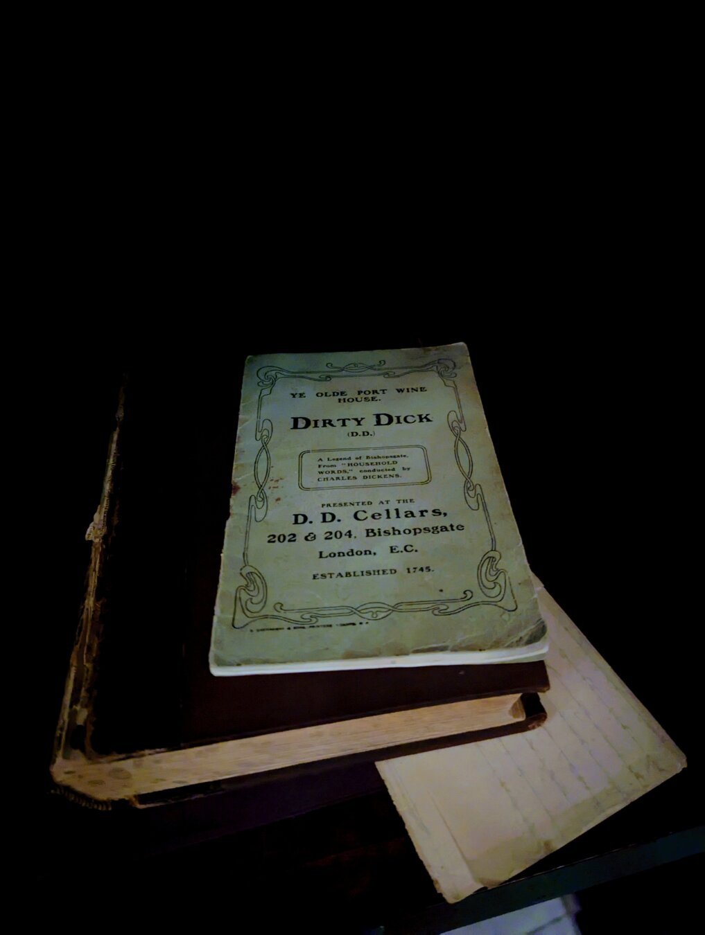 Photo of an old brochure with the text:

YE OLDE PORT WINE HOUSE.

DIRTY DICK (D.D.)

A Legend of Bishopsgate. From "HOUSEBOLD WORDS, conducted by CHARLES DICKENS.

PRESENTED AT THE

D. D. Cellars, 202 & 204, Bishopsgate London, E.C.

ESTABLISHED 1745.
