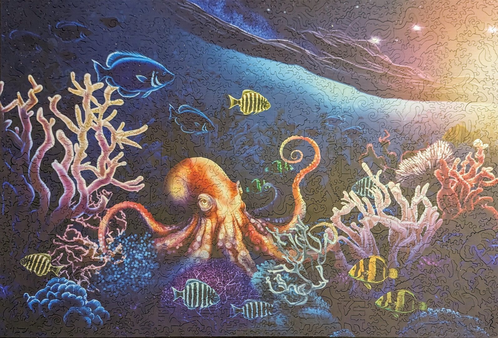 Photo of a completed wooden puzzle of a great Pacific octopus surrounded by coral, fish, and waves.