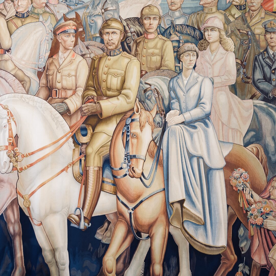 A detailed tapestry shows a large group of people on horseback, dressed in military uniforms and formal clothing. At the center, a man in a brown uniform with gloves and a serious face rides a tan horse. Beside him is a woman in a long blue dress, sitting side-saddle on a light brown horse decorated with flowers near its tail. She holds the reins gently and looks ahead calmly. Another man in a red-collared uniform rides a white horse to the left. The background is filled with many men and women, all on horses, wearing different styles of uniforms and hats. The scene feels grand and historical, with soft pastel colors and strong facial expressions. The group appears to be part of a parade or important event, with attention to detail in clothing, horses, and faces.