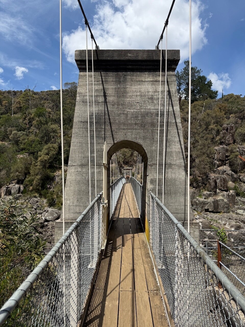 The footbridge crossing the South Esk River. A view through the first archway that carries the ropes that form the bridge way.