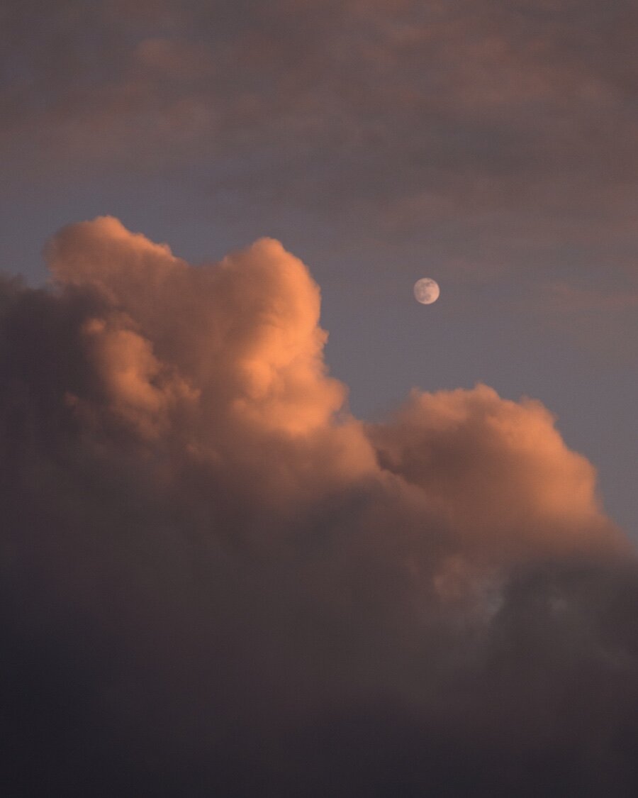 Reflets rosés sur des nuages lors d'un couché de soleil avec apparition la pleine lune