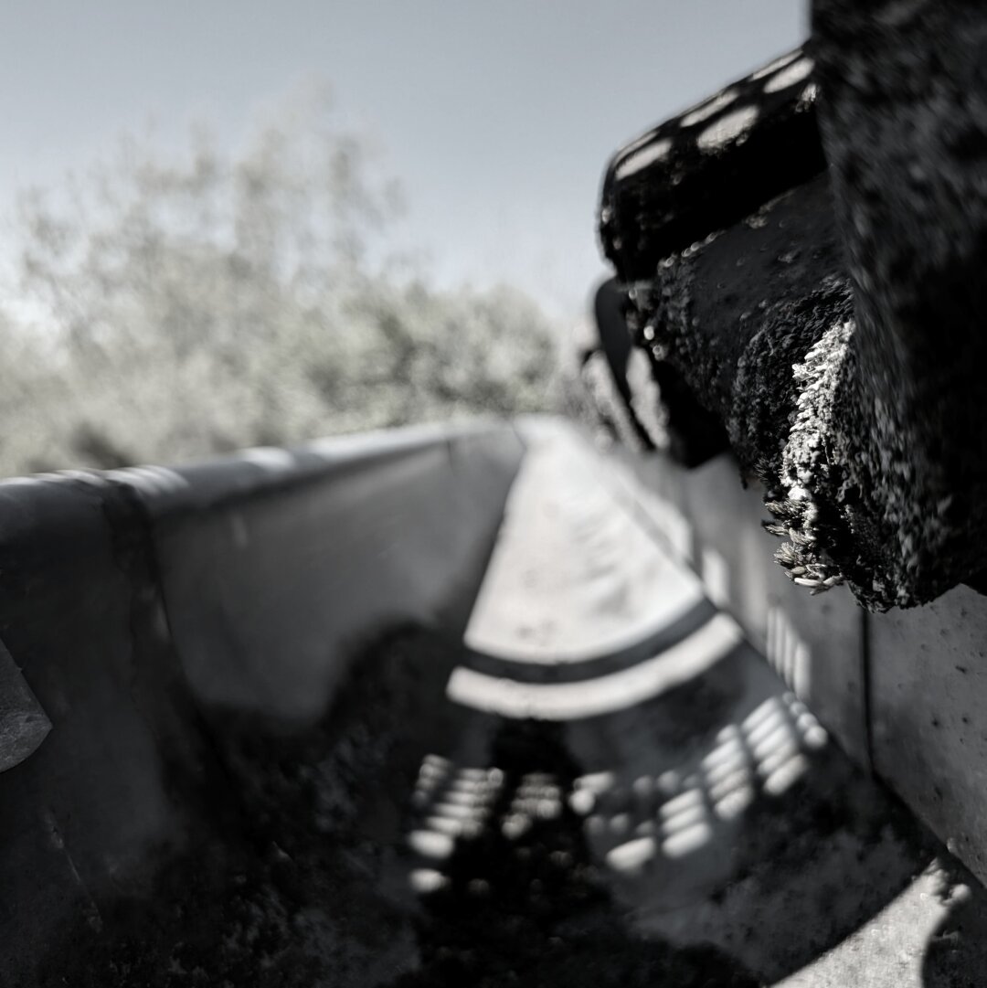 black and white photo locking down a roof drain, a corner of the roof on the right is in focus while the rest of the image is blured.