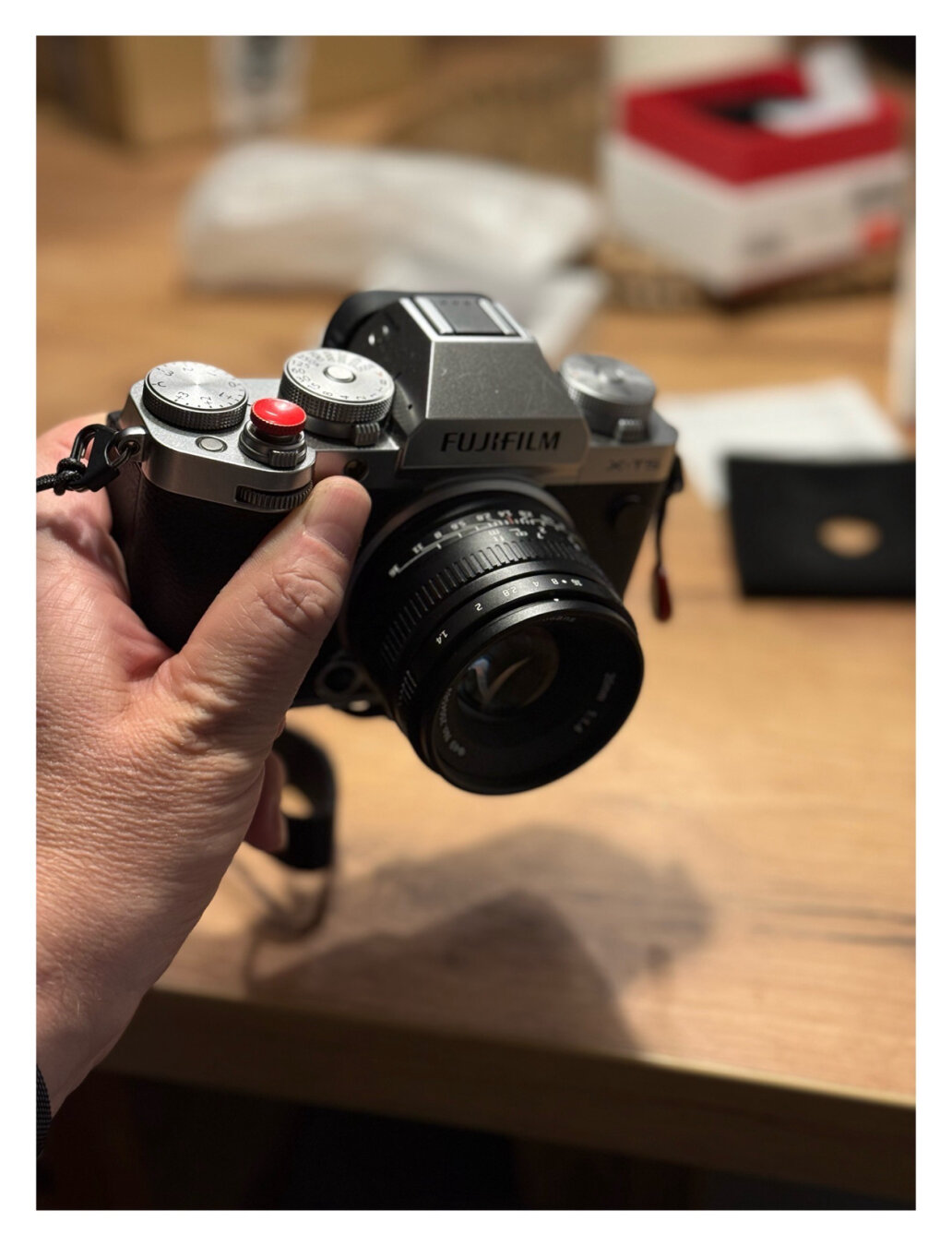 Ich halte die Fuji X-T5 in der Hand, eine Kamera im Silber-schwarzem Retro Look. Ein schwarzes Objektiv ist vorne befestigt. Ich halte die Fuji X-T5 in der Hand, eine Kamera im Silber-schwarzem Retro Look. Ein schwarzes Objektiv ist vorne befestigt.