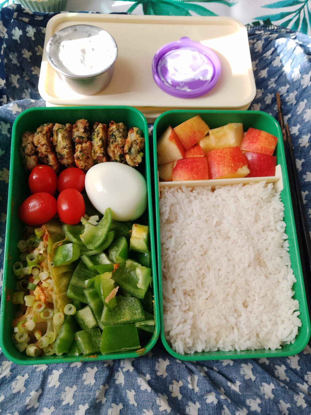 Green bento box with lots of vegetables, an egg, rice and apple.