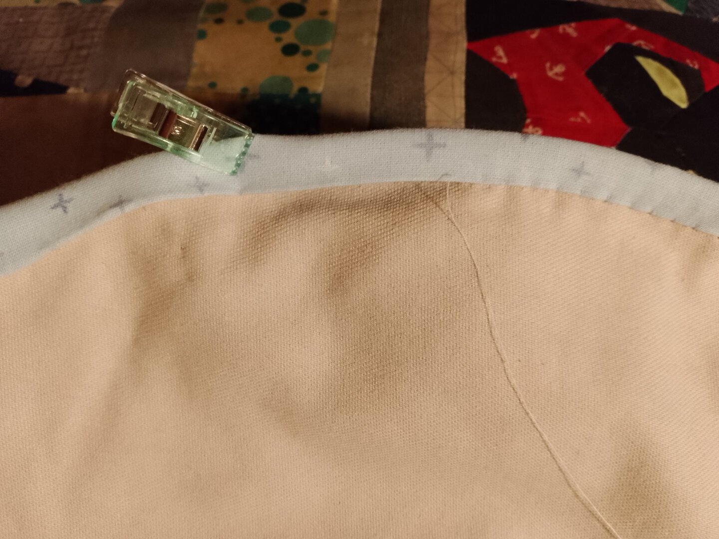 Inner part of a bag. The egde is wrapped in binding which is sewn around half the edge. A snap holds the un-sewn part shut.