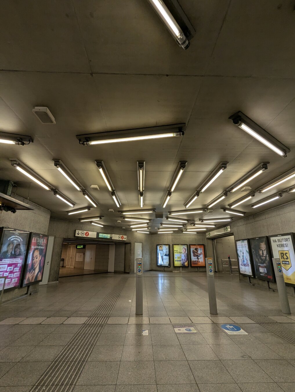 Eingang einer U-Bahn-Station in Budapest. An der Decke viele Leuchtröhren unterschiedlicher Position und Ausrichtung.