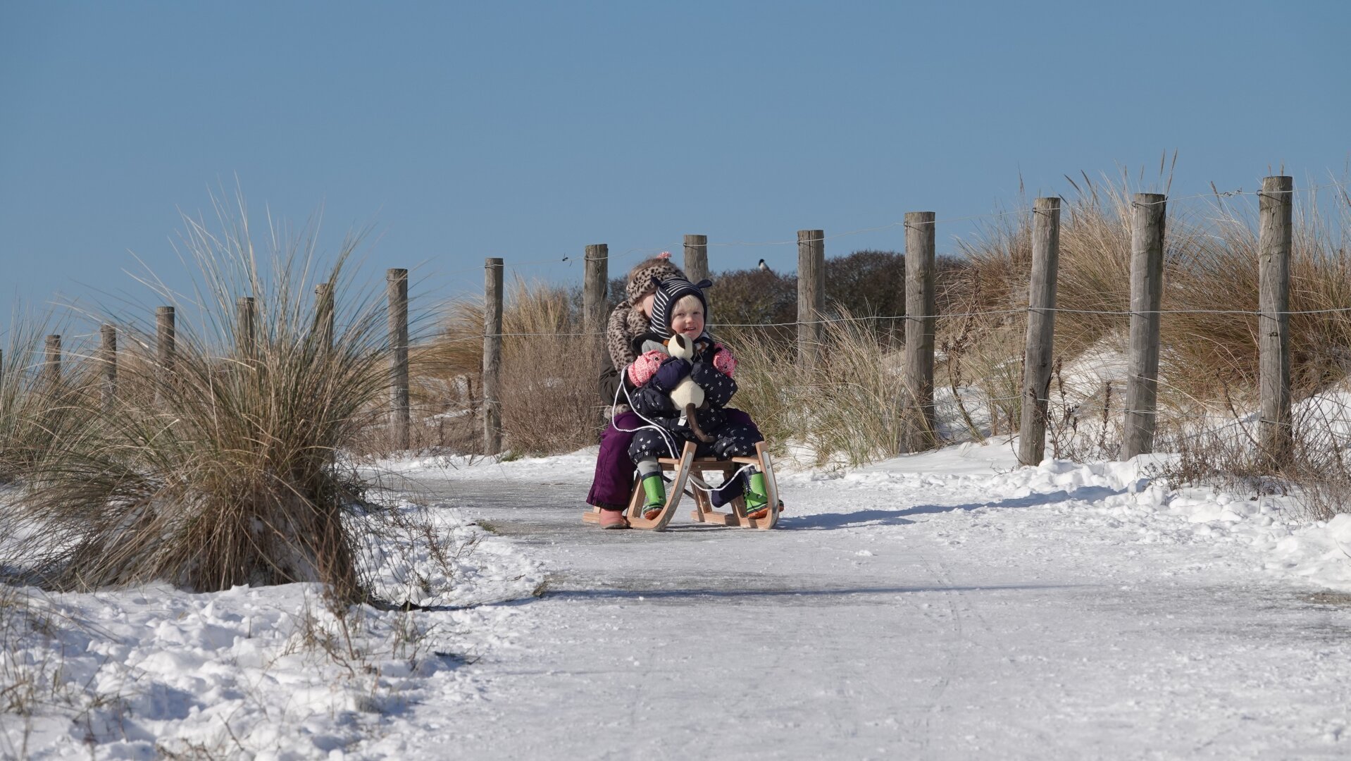 2 kids sledding in the snowdunes