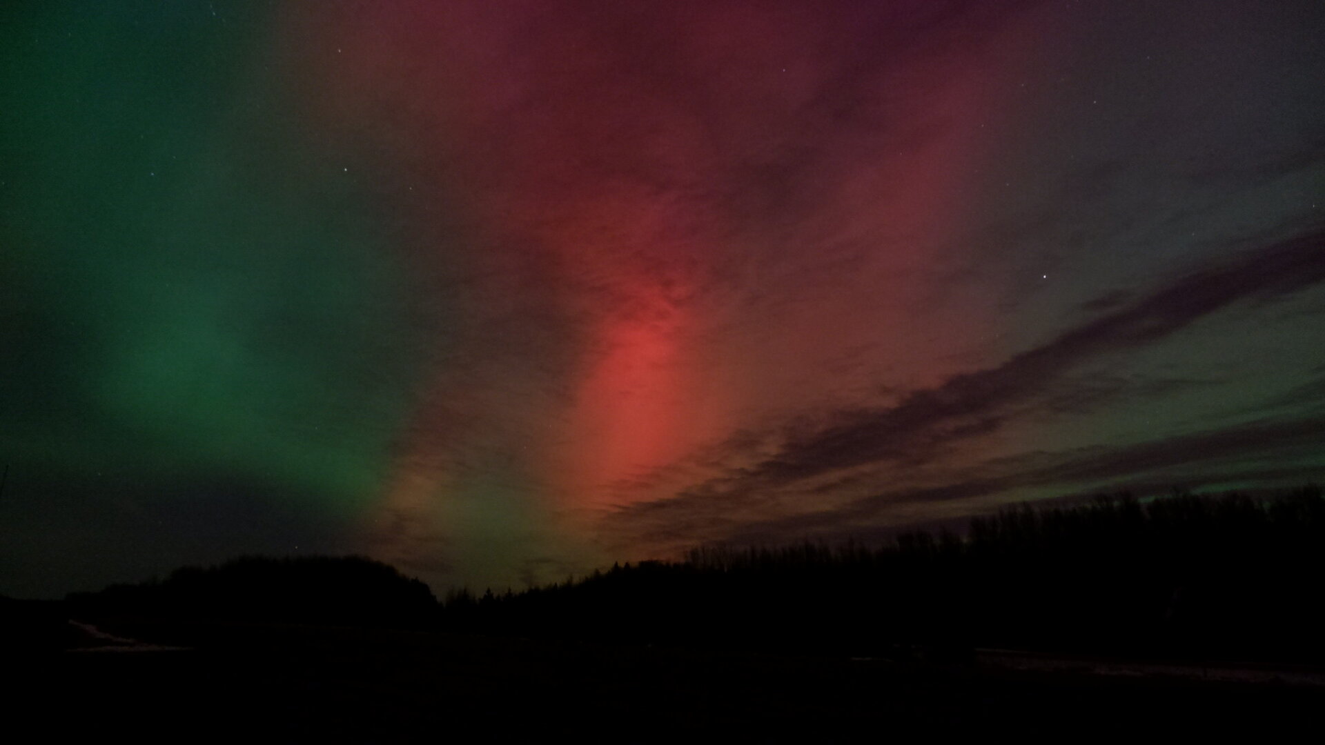 Showing bright aurora in the night sky. Mostly red, pink and green along the edges.