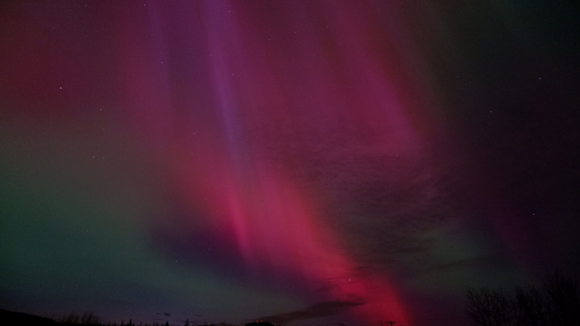 Showing bright aurora in the night sky. Mostly red, pink and green along the edges.