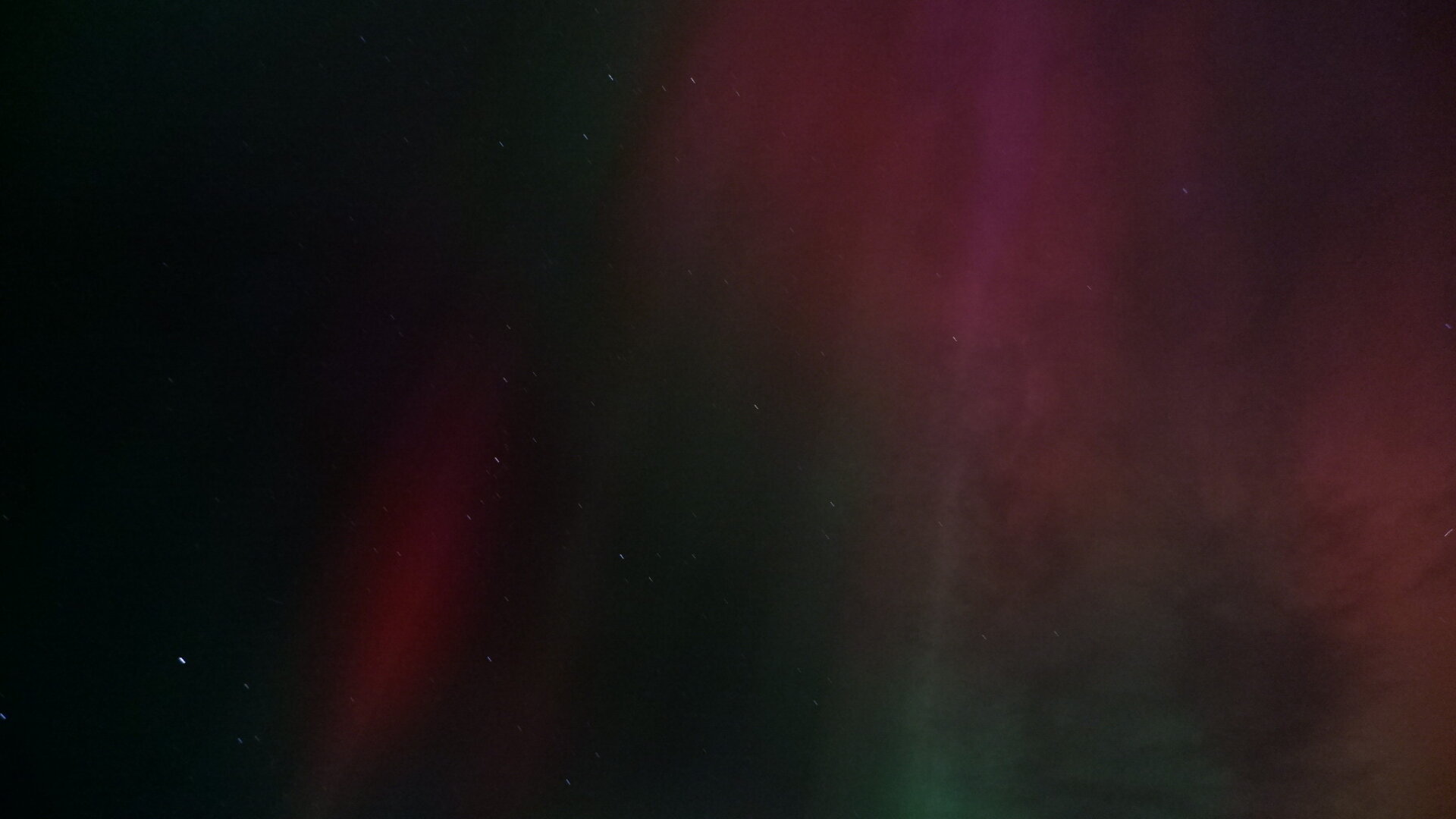 Showing bright aurora in the night sky. Mostly red, pink and green along the edges.