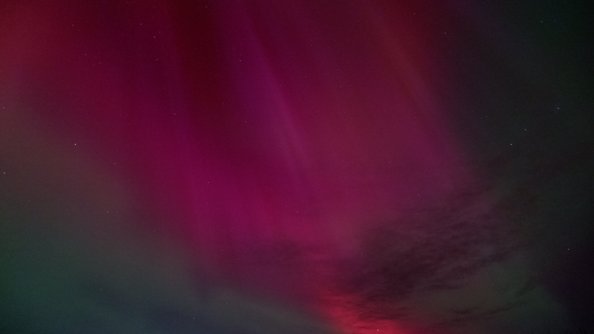 Showing bright aurora in the night sky. Mostly red, pink and green along the edges.
