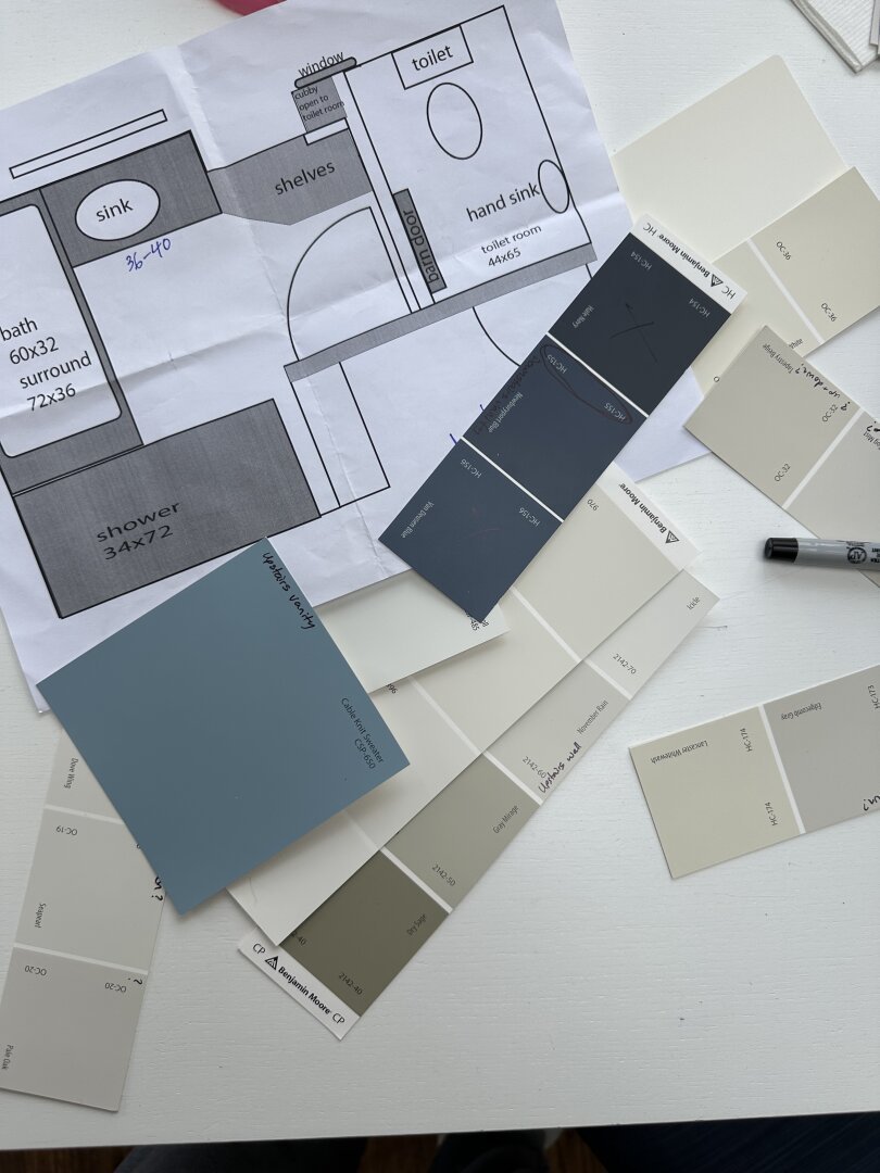 Floor plan of a bathroom on a table surrounded by blue and beige paint chips