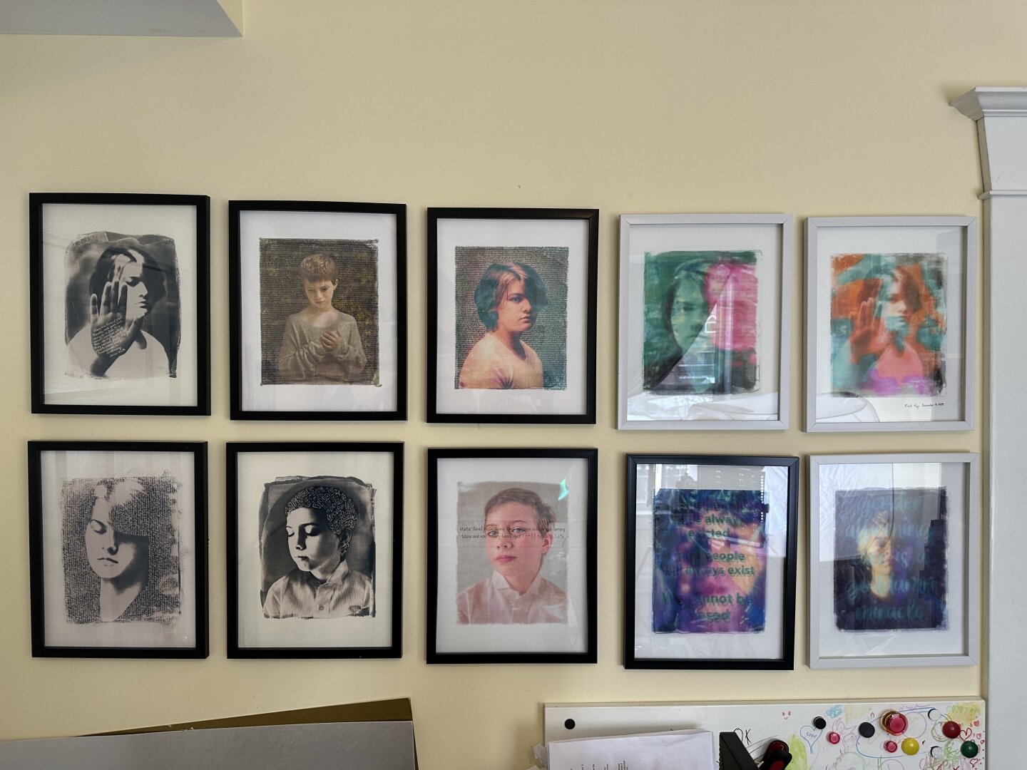 A wall with 10 framed pictures of kids, some black and white and some colour, most of them with text on them.