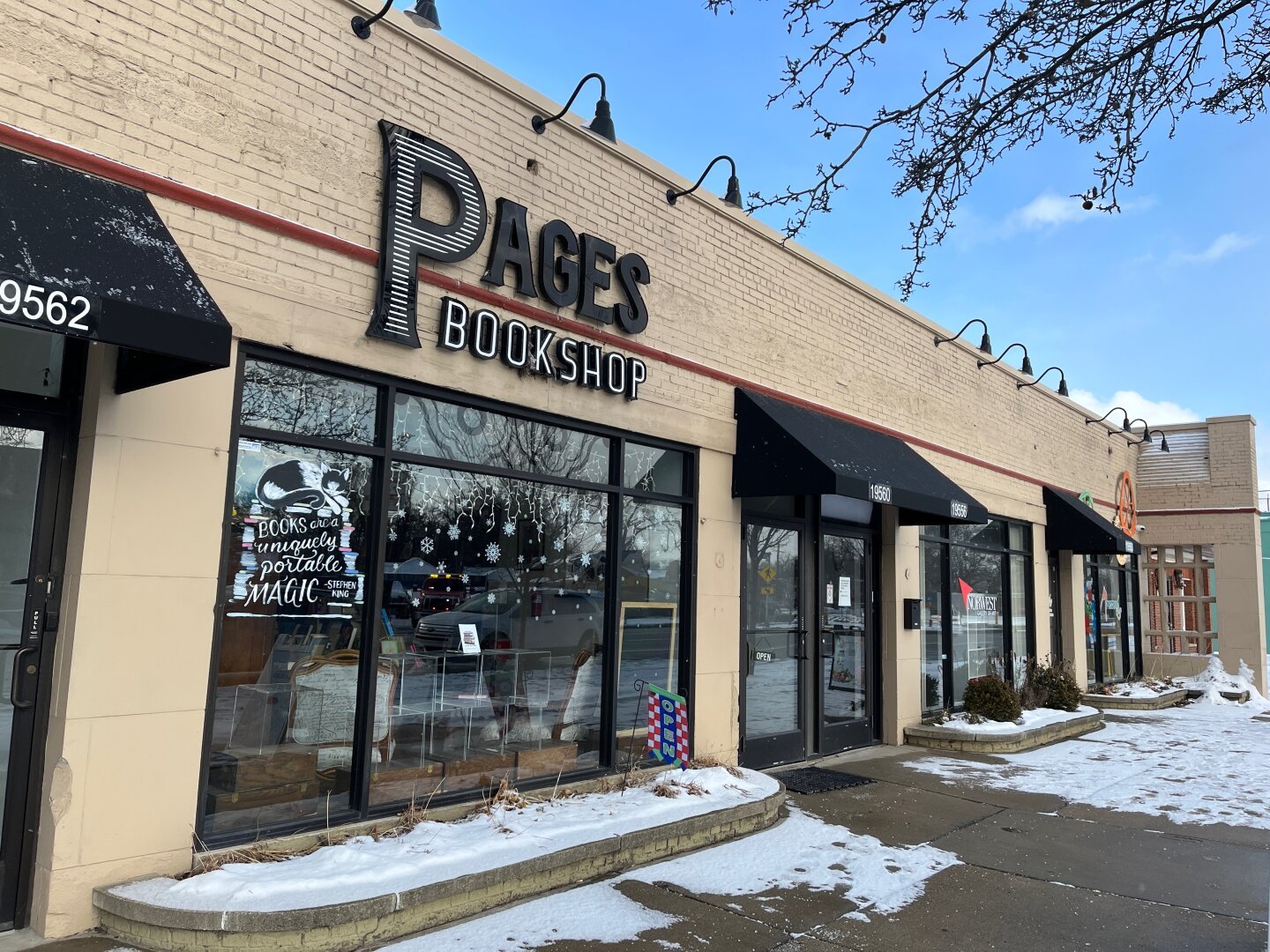 Front of a bookstore called Pages. It’s a sunny day with snow on the ground. The building’s bricks are tan